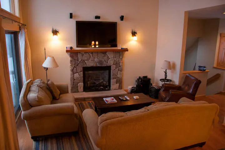 A living room with a fireplace, couches, a coffee table, and a flat-screen TV.