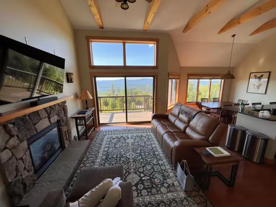 A living room with a fireplace, large windows, and a view of the mountains.